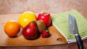 a wooden table with fruits, vegetables, and knife