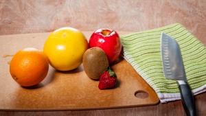 a wooden table with fruits, vegetables, and knife