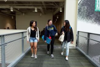 Three students talking and laughing as they walk to class