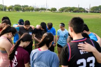 Group of Asian American students holding hands praying