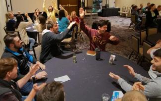 Group of students playing game at tables, cheering and smiling