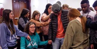 Group of students gathered around praying over another student