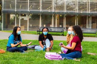 Group of students gathered outside sitting in grass singing