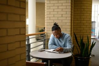 One student sitting at table reading Bible