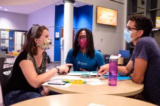 Student and campus ministers meeting at tables in lounge