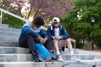 Two students praying for each other outside on stone steps