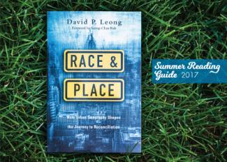 Book cover of Race & Place (blue image of cityscape) laid out on the grass with label: Summer Reading Guide 2017