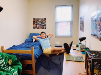 Student sitting with legs propped up on desk in freshmen dorm room