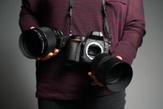 Two hands holding a camera and changing its lenses