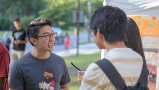 Stephan on campus talking with two students outside