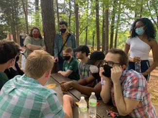 Calvin with group of fellow InterVarsity students seated at picnic table surrounded by trees