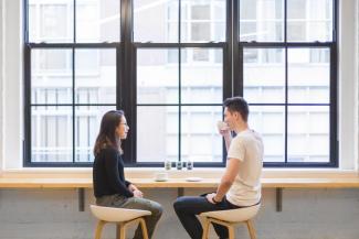 Young man and woman talking, seated in coffee shop