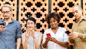 Group of people all staring at smartphones standing side by side