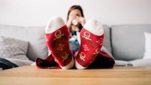 Woman sitting on couch wearing red Christmas socks propped up on table holding mug