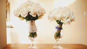 Two bouquets of white roses in glass vases on table