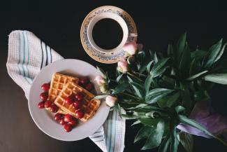 Plate of waffles with coffee on table next to plant