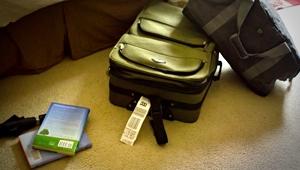 Luggage tipped over on the floor next to couch and stack of books