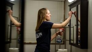 Woman cleaning bathroom mirror