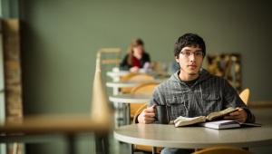 a young man sitting a table with his Bible open