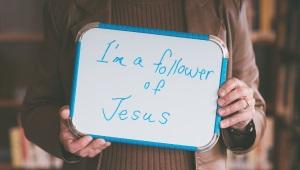 Person holding whiteboard that says "I am a Follower of Jesus"