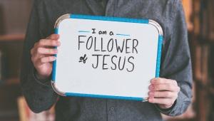 Man holding whiteboard that says "I am a Follower of Jesus"