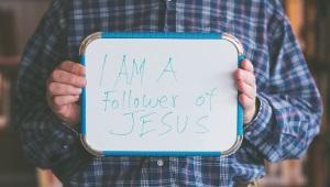 Man holding whiteboard that says "I am a Follower of Jesus"