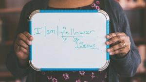 Woman holding whiteboard that says "I am a Follower of Jesus"