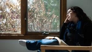 a woman with a Bible on her lap looking through a window