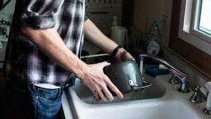 Man washing dishes in kitchen sink