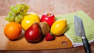 Variety of fruit on cutting board beside kitchen knife and towel