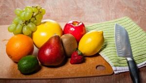 a wooden table with fruits, vegetables, and knife