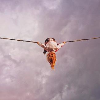 Person draped over tightrope barely holding on