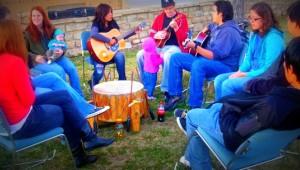 Native family gathering of all ages talking and playing music with guitars and drum