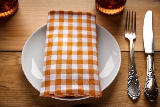 table place setting on wood table with brown and white napkin