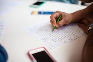 Closeup of person doing manuscript Bible study writing on piece of paper covered in writing and notes