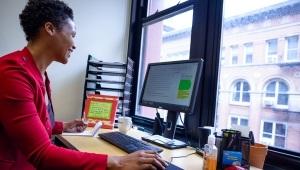 Woman sitting at computer in office overlooking cityscape