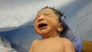 Closeup of newborn crying held by doctor