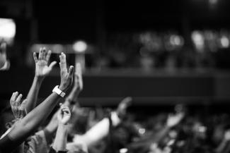 Black and white photo of many hands raised in worship