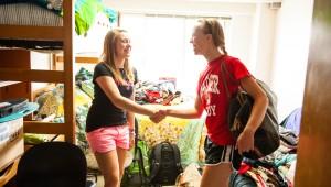 Two students shaking hands in a dorm room
