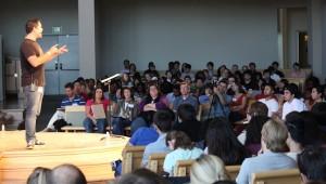 a large group of students listening to a man speak 