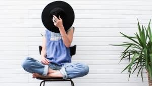 woman sitting cross-legged with a wide-brim hat covering her face