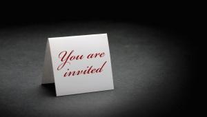 folded white paper that stands up and says "you are invited" in red letters