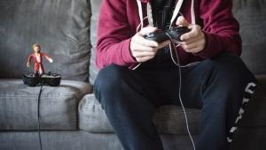 Jesus action figure standing on top of video game controller next to a person playing video games