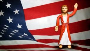 Jesus action figure standing in front of American flag backdrop