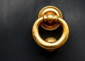 a gold door knocker on a black door