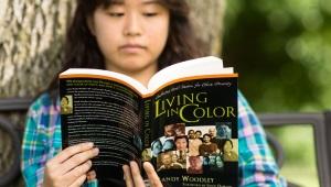 Native female student reading Living in Color book outside