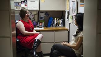Two women having conversation in office cubicle