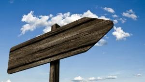 A wooden signpost in front of a blue-sky backdrop.