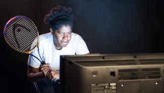 a woman holding a tennis racket and watching television
