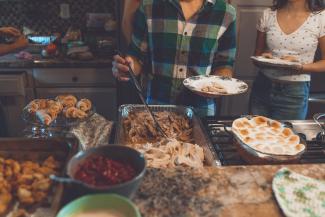 Person picking food on a tray from a Thanksgiving feast